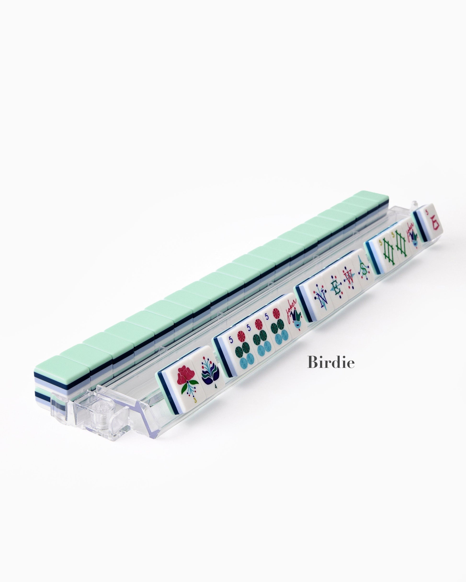 The Oh My Mahjong Tile Collection features a row of hand-painted tiles on a clear rack, each tile displaying unique symbols and "Birdie" for an elevated gaming experience.