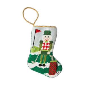 The Bauble Stockings Christmas Birdie Nutcracker Needle Point Stocking features a golf-loving nutcracker design and gold hanging loop—festive holiday decor for any golf enthusiast.