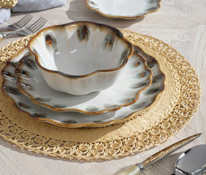 From Blue Pheasant’s Amoria Dinnerware Collection, a white ceramic bowl and two brown-edged plates with vintage charm are stacked on a round woven placemat atop a wooden table with cutlery beside them.
