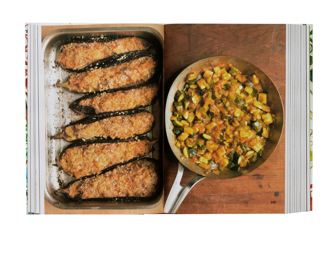 Four breaded eggplants in a baking dish next to a pan of mixed vegetables, displayed in an open Phaidon Spain: The Cookbook featuring Spanish recipes.