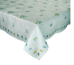 The Kim Seybert Lima Seafoam Tablecloth, featuring a floral and leaf pattern in blue, green, and yellow inspired by Peruvian embroidery, is draped over a rectangular table.