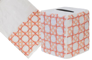 The Cane Bath Collection, Coral by Haute Home features a hand-embroidered tissue box cover with an orange lattice pattern on exquisite Italian linen, paired elegantly with a napkin against a pristine white background.
