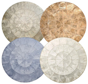 Four Capiz Placemats by Kim Seybert, featuring textured, segmented patterns in silver, gold, blue, and white, create a stylish table backdrop when arranged in a two-by-two grid.
