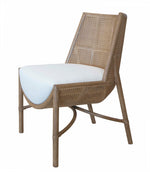 A wooden chair with a woven Wild & Wooly Sea Salt Rattan backrest and an upholstered white cushioned seat, featuring angled legs and a curved design, the Taru Side Chair by McGuire Furniture.