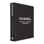 A black hardcover coffee table book, "Chanel: The Karl Lagerfeld Campaigns" by Abrams, features striking photography and bold white text on the cover and spine.