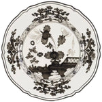 The Oriente Italiano Albus Dinnerware Collection by Ginori 1735 features porcelain plates with scalloped edges and intricate black floral and geometric designs on a white background, inspired by timeless elegance.