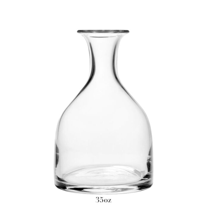 The Classic Carafe Collection by William Yeoward Crystal features a clear glass carafe with a wide base, narrow neck, and flared rim—ideal for serving wine or water. Holds 35 ounces and is shown against a plain white background.