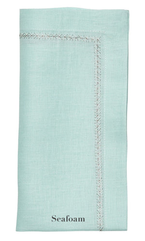 The Kim Seybert Classic Napkin Set features neatly folded light seafoam green linen napkins with embroidered borders and "Seafoam" printed at the bottom—perfect for elegant décor.