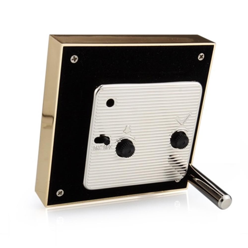 The Addison Ross Gold Square Alarm Clock Collection features a brass and black design with knobs, a lever, and a luxurious velvet back, resembling a compact musical instrument or electronic device, isolated on a white background.