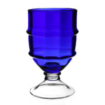 The Cotswold Footed Hurricane Collection by William Yeoward Crystal features a blue glass goblet with a clear stem and round base, inspired by traditional glassblowing, shown against a white background.