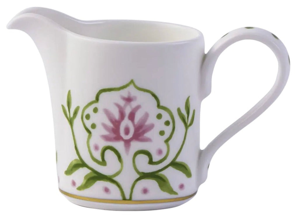 The Cobblers Cove Camelot Dinnerware Collection by Royal Crown Derby features a white ceramic cream pitcher with pink floral and green vine accents—an elegant touch for luxury boutique hotel settings.