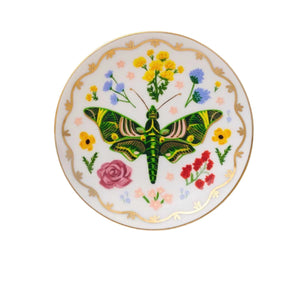 The Curio Desk Accessory Collection round porcelain plate by Rifle Paper Co. showcases a central green moth, illustrated bugs, bright florals, and a gold-trimmed edge—ideal for garden lovers.