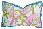 The Enchanted Garden Bamboo Outdoor Lumbar Pillow by Associated Design features a pink and green floral pattern on white with teal fringe trim. Handmade in the USA and filled with custom-poly for lasting comfort and style.