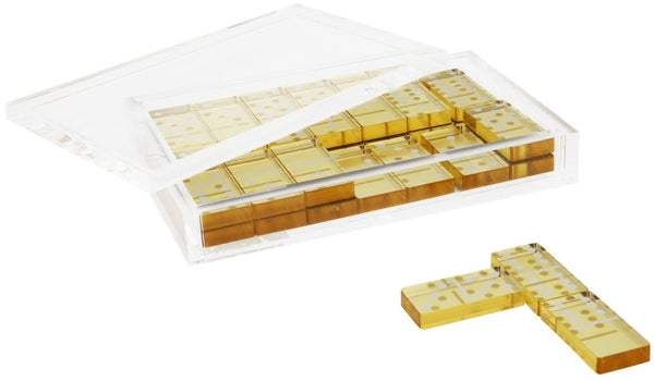 A Tizo Design Lucite Domino Set Collection containing multiple slots with yellowish-brown dominoes, some of which are visible through the clear lid, with two individual dominoes lying in front outside the case, perfect