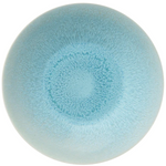 The Jars Vuelta Ocean Blue Collection features a round, light blue ceramic plate with a speckled ocean glaze gradient radiating from the center, adding timeless elegance to any table.