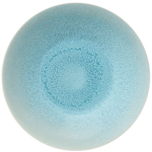 The Jars Vuelta Ocean Blue Collection features a round, light blue ceramic plate with a speckled ocean glaze gradient radiating from the center, adding timeless elegance to any table.