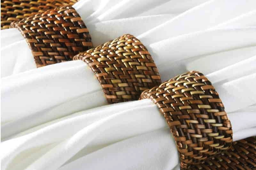 Three white cloth napkins, each held by a Calaisio Woven Napkin Ring handmade from South Pacific water-vines, are arranged side by side on a surface.