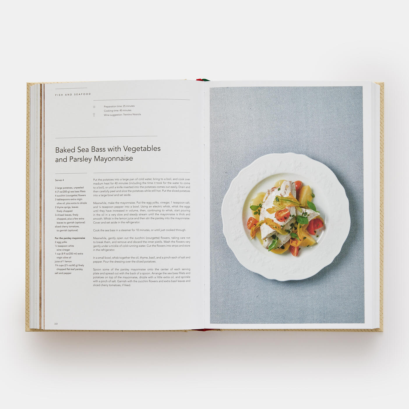 An open copy of "Eataly: Contemporary Italian Cooking" by Phaidon presents a delightful recipe for "Baked Sea Bass with Vegetables and Parsley Mayonnaise" on the left page, while the right page features a vibrant photo of this Italian home cooking masterpiece.