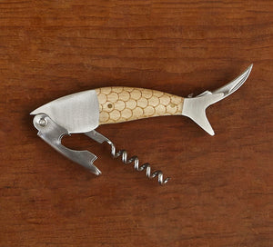 The Finest Catch 3 in 1 Bottle Opener by Two's Company features a fish-shaped design with corkscrew, foil cutter, and wine knife—ideal as a unique fishing gift and shown here resting on a wooden surface.