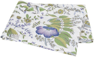 The Matouk Pomegranate Roman Linen Bedding Collection in Lilac features a folded white linen fabric with a floral pattern of green leaves and purple, blue, and yellow flowers.