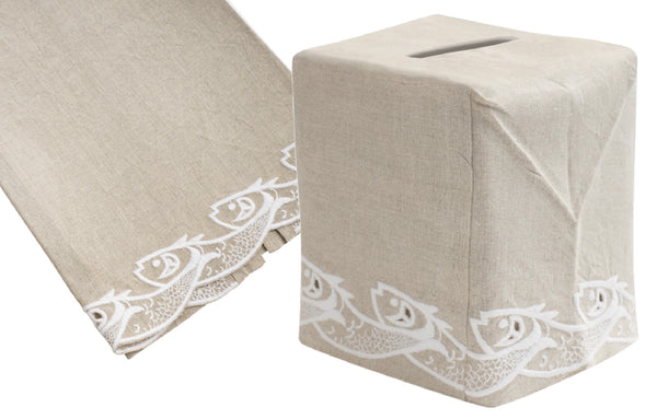 Beige Italian linen tissue box cover from the Haute Home Scrollfish Collection, featuring white floral hand-embroidered designs, is displayed on a flat surface and as fitted over a box.