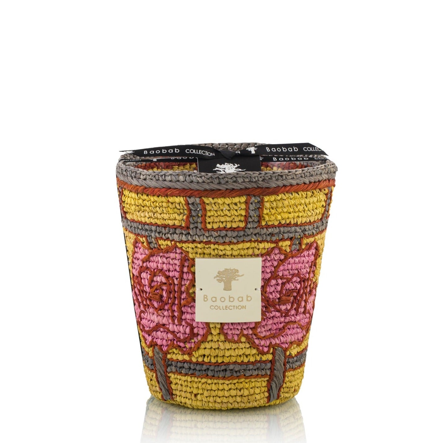 A scented Baobab Collection Frida Draozy Magda candle with a detailed, woven pattern on the exterior in pink, yellow, and beige, against a white background.