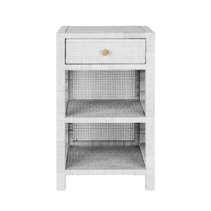 The Isla Nightstand Collection by Made Goods features a white wicker nightstand with basket weave design, one soft-close drawer, and two open shelves, shown against a white background.