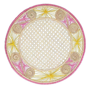 The Jungle Placemat by Mercedes Salazar is a round woven mat made from natural raffia, featuring a central lattice design, bright yellow and pink thread accents, and spiral details along the outer edge.