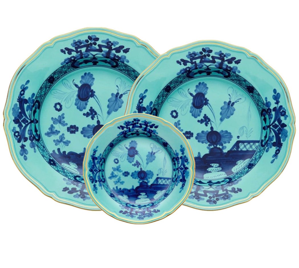 Three Oriente Italiano Iris with Gold plates by Ginori 1735, featuring turquoise glaze, blue floral patterns, and gold trim, are arranged with a small plate in front of two larger plates to showcase Italian elegance.