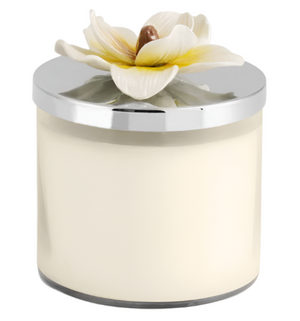 The Michael Aram Magnolia Candle features soothing white magnolia fragrance in a glass jar with a silver lid and a decorative ceramic flower.
