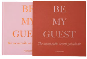 Two "Be My Guest Book" guest books by PrintWorks in rust and pink are shown—ideal for capturing memories and bringing stylish flair to your home.