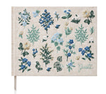 The Wildwood Embroidered Guest Book by Riffle Paper Co. features beige fabric, blue, white, and green floral embroidery, and "Guests" stitched in the corner—an elegant keepsake for special events.