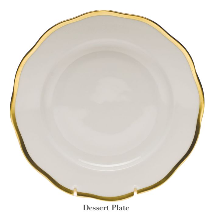 The Herend Gwendolyn White and Gold Collection dessert plate features a scalloped edge and 24k gold trim, displayed upright on a stand—a perfect piece for artistic appreciation.