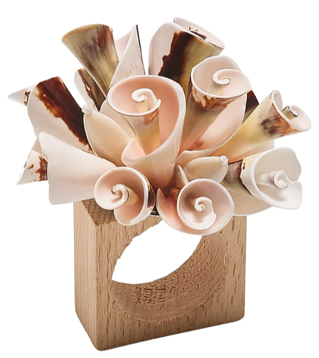 The Kim Seybert Seashell Burst Napkin Ring features an arrangement of curled, shell-like pieces in beige and brown, adding a decorative touch perfect for seaside gatherings.