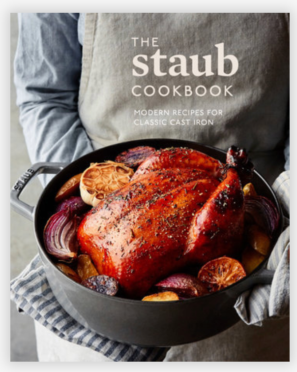 A roasted chicken in a Staub enameled cast-iron pot surrounded by onions and garlic is pictured. The text reads: "The Staub Cookbook: Modern Recipes for Classic Cast Iron" by Penguin Random House.