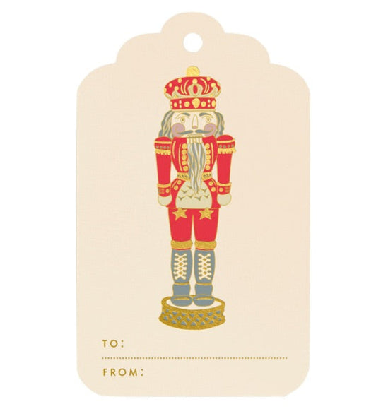 Crane’s Nutcracker Gift Tag Set features red and gold nutcracker soldier designs with “TO:” and “FROM:” spaces at the bottom for easy gifting.