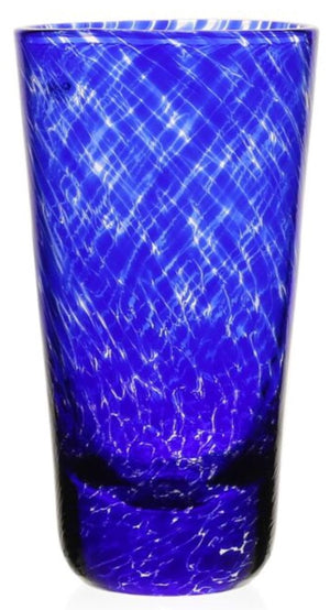 A tall, cobalt blue glass from the Vanessa Blue Drinkware Collection by William Yeoward Crystal features a textured crisscross pattern that creates an optical illusion as it reflects light.