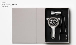 PrintWorks The Essentials Cocktail Tools is a boxed kit with a metal jigger, hawthorne strainer, and ice tongs nestled in foam—ideal for cocktail enthusiasts seeking quality mixology tools.