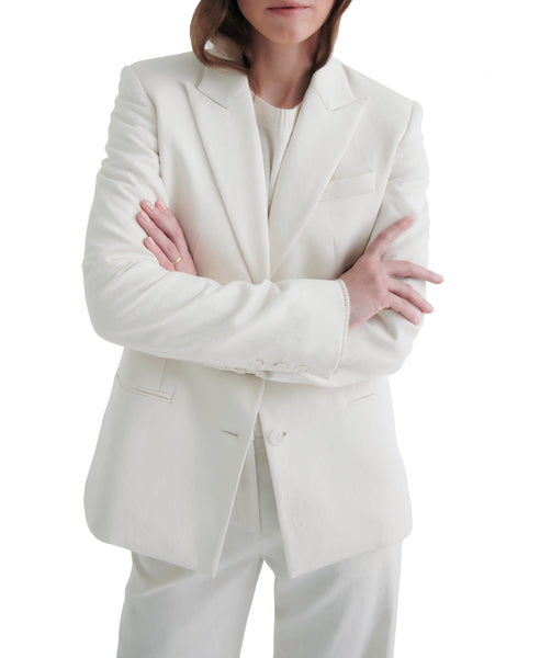 Woman in a white single-breasted TWP Husband Linen Jacket crossing her arms, standing against a plain white background.