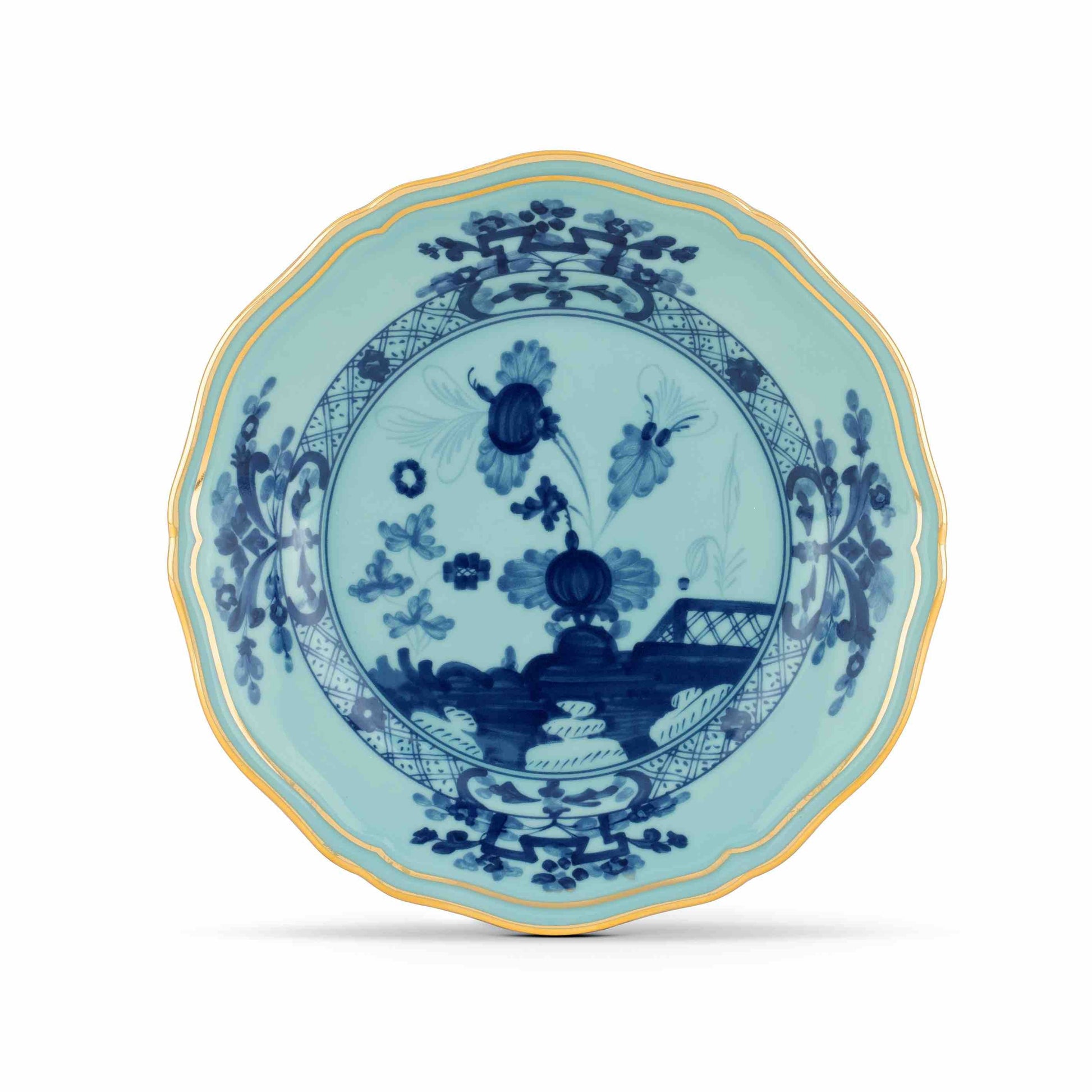 The Oriente Italiano Iris with Gold Dinnerware Collection by Ginori 1735 features scalloped porcelain plates adorned with blue floral and geometric patterns on a light turquoise background, finished with an elegant gold rim.