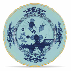 The Oriente Italiano Iris with Gold Dinnerware Collection by Ginori 1735 features a round porcelain plate with scalloped edges, blue floral and landscape patterns on pale blue, and a gold rim inspired by Italian elegance.