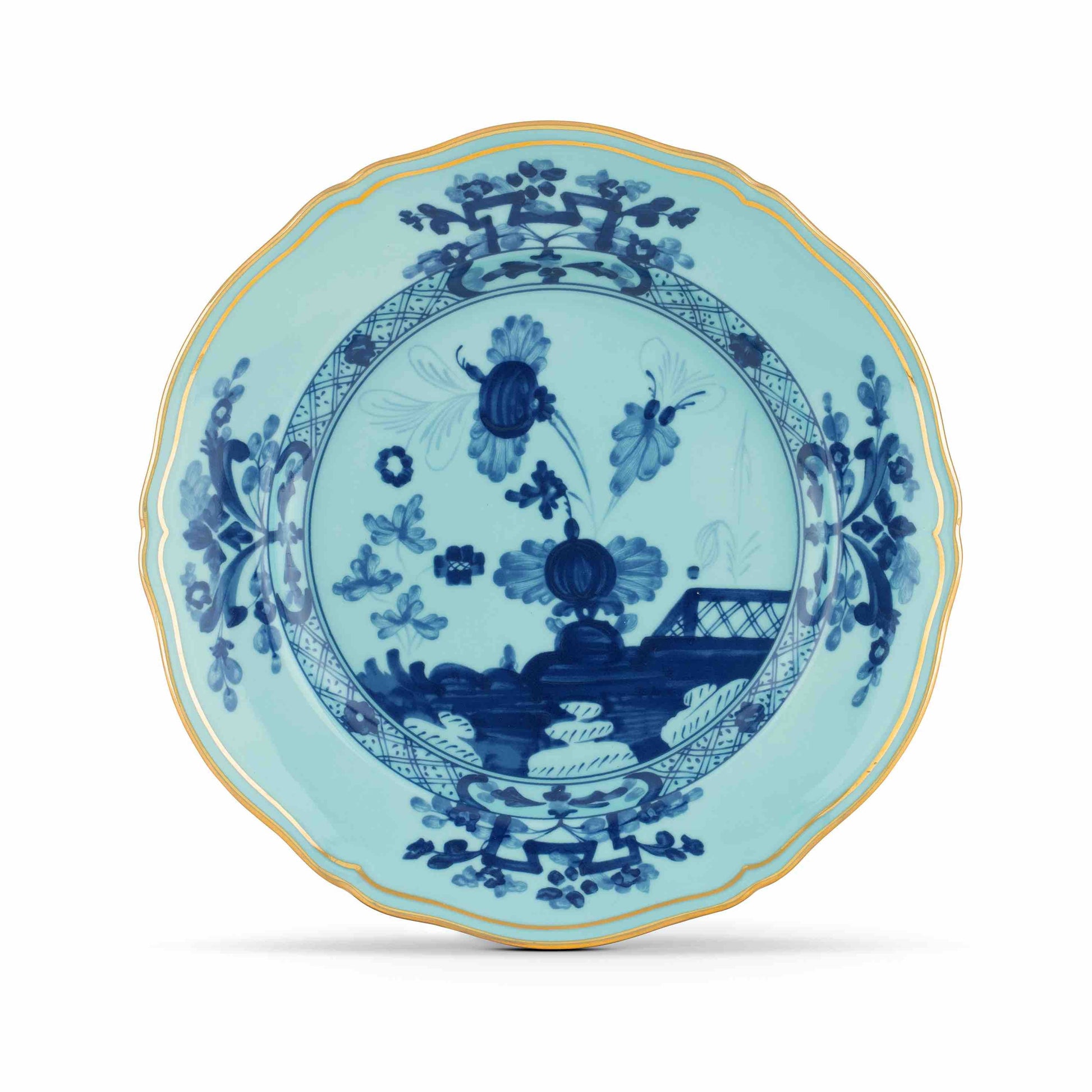The Oriente Italiano Iris with Gold Dinnerware Collection by Ginori 1735 features blue and white porcelain plates with floral and geometric patterns, scalloped edges, and gold trim, showcasing Italian elegance and exquisite craftsmanship.