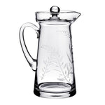 The Jasmine Pitcher Collection by William Yeoward Crystal features a clear glass pitcher with handle and lid, adorned with an elegant leaf and branch etching reminiscent of a cherished wedding gift or jasmine’s delicate beauty.