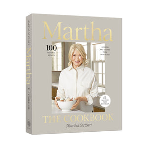 The cover of "Martha: The Cookbook 100 Favorite Recipes" by Penguin Random House shows Martha Stewart with a bowl of eggs, and text highlights 100 favorite recipes and the book’s bestseller status.