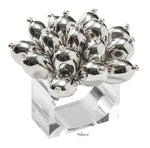 The Jubilee Napkin Ring by Kim Seybert features a cluster of shiny, silver bulb-shaped ornaments on a clear square band—ideal for festive occasions or elevating your table setting. Labeled "Silver" below.