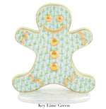 The Herend Gingerbread Man Collection features a porcelain gingerbread-shaped figure with hand-painted green and gold patterns, gold buttons, and accents on a white base. "Key Lime Green" appears below for a touch of artistic flair.