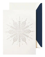 The Crane Silver Snowflake Card Set features an embossed white snowflake card, ideal for the holidays, shown partially inside a white envelope with a dark blue lining.