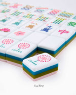 A close-up of vibrant, hand-painted tiles from the Mahjong Tile Collection by Oh My Mahjong, with a "JOKER" tile featuring a dotted pink design in the foreground for an enhanced gaming experience.