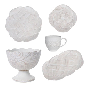 Five pieces from Juliska’s Le Panier Mystic Knot Collection—two plates, a bowl, a cup, and an oval platter—feature French basket weave-inspired braids and are displayed on a crisp white background.