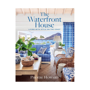 Cover of "The Waterfront House" by Abrams, showing a coastal living room in blue and white with wicker furniture and ocean views—a welcoming seacoast home merging interior comfort with outdoor beauty.